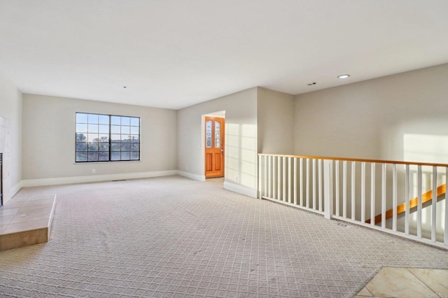 empty room with a tiled fireplace and light colored carpet