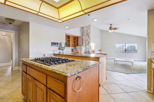 kitchen featuring lofted ceiling, stainless steel gas cooktop, light stone counters, light tile patterned floors, and a kitchen island