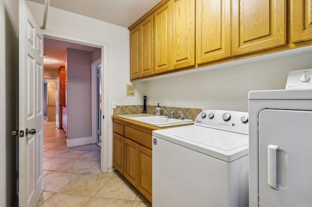 clothes washing area with cabinets, washing machine and dryer, sink, and light tile patterned floors