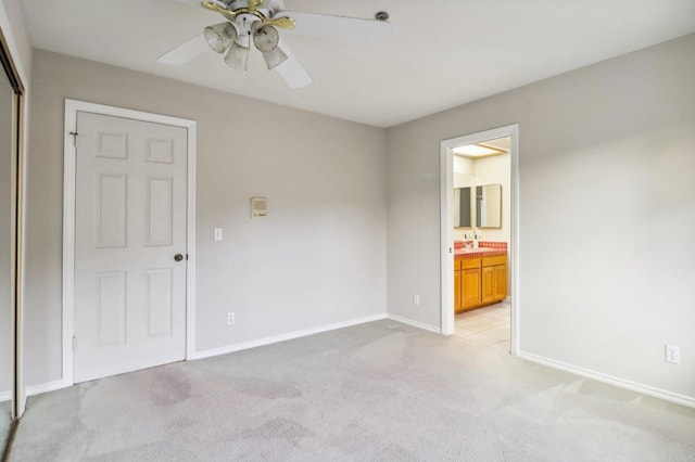 unfurnished bedroom featuring ceiling fan, light colored carpet, and ensuite bath