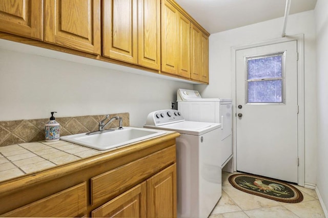 laundry room featuring sink, washer and clothes dryer, cabinets, and light tile patterned flooring