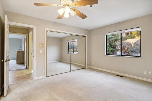 unfurnished bedroom featuring light carpet, ceiling fan, and a closet