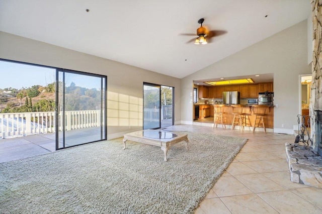 tiled living room with ceiling fan and high vaulted ceiling