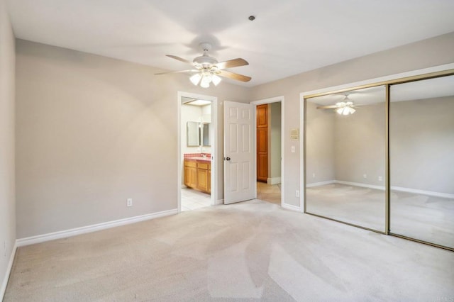 unfurnished bedroom featuring ensuite bathroom, light carpet, ceiling fan, and a closet