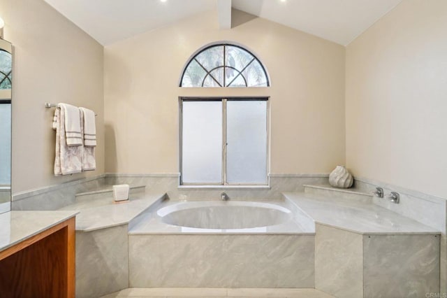 bathroom featuring vanity, lofted ceiling, and a bathtub