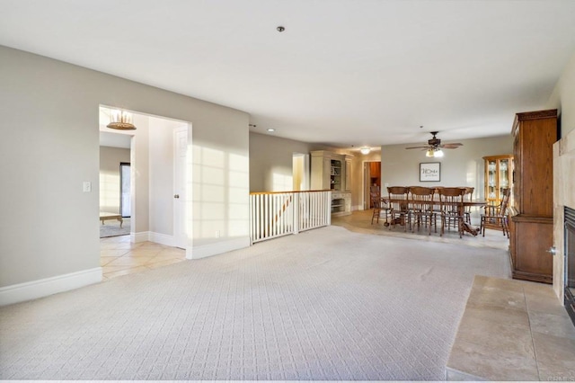 unfurnished living room with ceiling fan, light carpet, and a fireplace