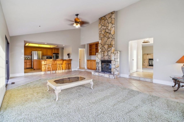 living room with light tile patterned flooring, a stone fireplace, ceiling fan, and high vaulted ceiling