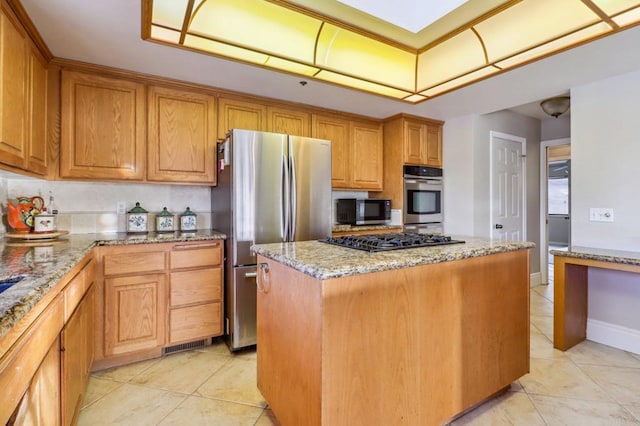 kitchen with light stone counters, appliances with stainless steel finishes, a center island, and light tile patterned flooring