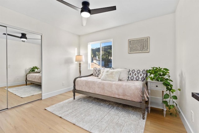 bedroom with ceiling fan, a closet, and wood-type flooring