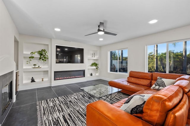 living room featuring ceiling fan, dark tile patterned flooring, and built in shelves