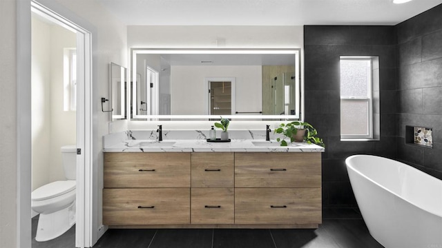 bathroom with tile patterned flooring, toilet, vanity, and a tub to relax in