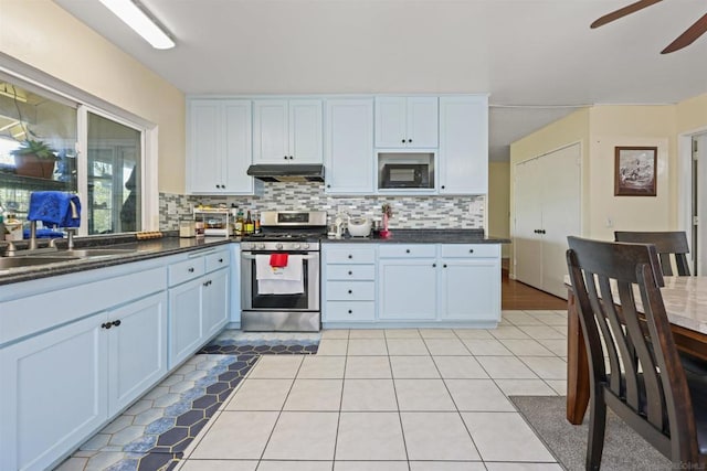 kitchen featuring white cabinets, black microwave, tasteful backsplash, and stainless steel gas range