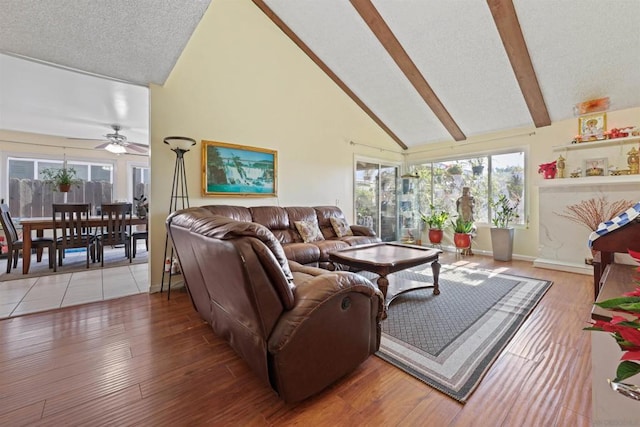 living room featuring ceiling fan, high vaulted ceiling, wood-type flooring, and beam ceiling