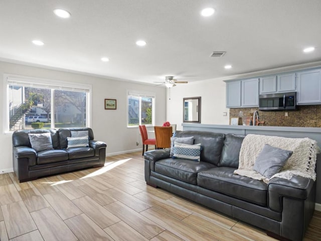 living room featuring crown molding, sink, and ceiling fan