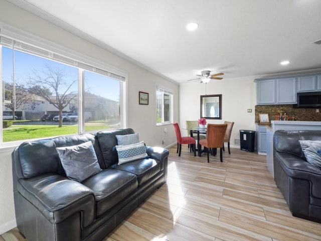 living room featuring ornamental molding, a wealth of natural light, ceiling fan, and light hardwood / wood-style flooring