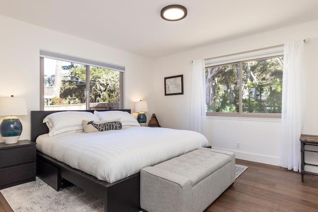 bedroom with multiple windows and dark hardwood / wood-style floors