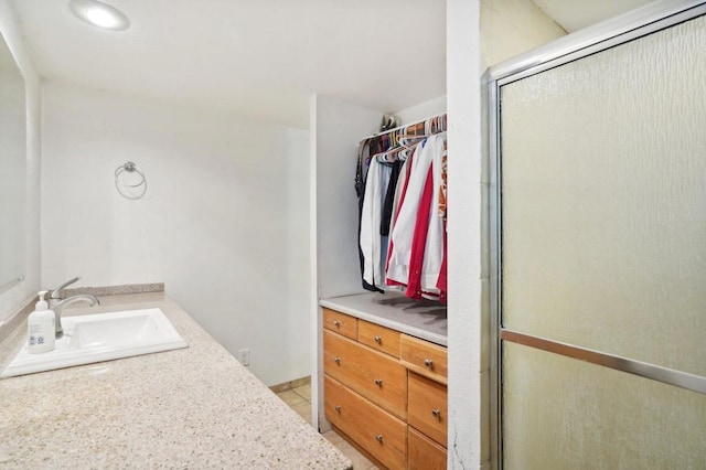 bathroom with a shower with shower door, vanity, and tile patterned flooring