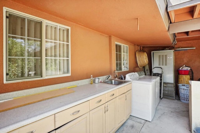 washroom with cabinets, sink, and washing machine and dryer