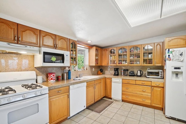 kitchen featuring tasteful backsplash, lofted ceiling, sink, white appliances, and light tile patterned floors