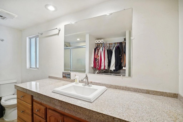 bathroom featuring toilet, vanity, and an enclosed shower