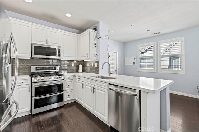 kitchen with white cabinets, kitchen peninsula, sink, and stainless steel appliances