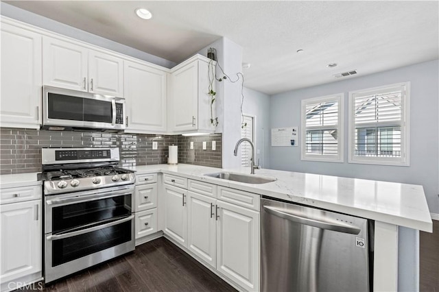 kitchen with kitchen peninsula, sink, stainless steel appliances, white cabinets, and dark hardwood / wood-style flooring