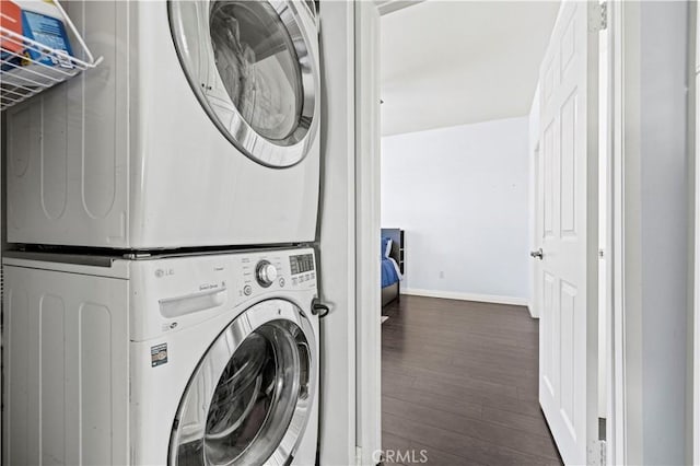 laundry room featuring stacked washer and dryer and dark hardwood / wood-style floors