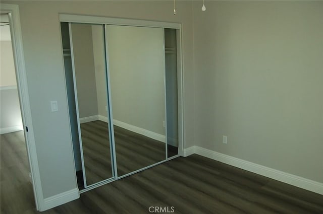 unfurnished bedroom with dark wood-type flooring and a closet