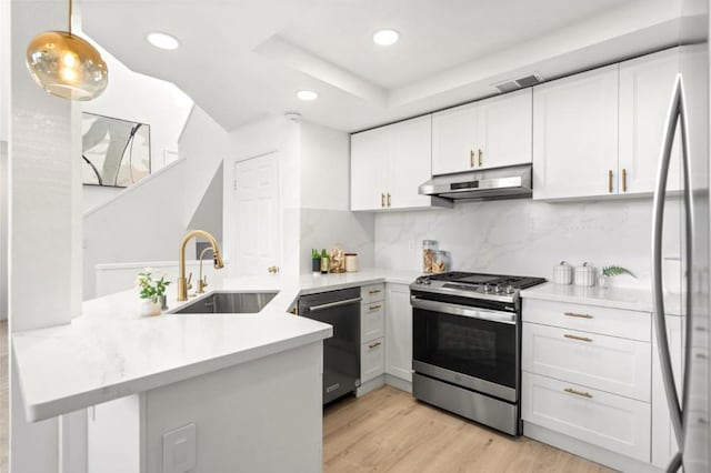 kitchen with hanging light fixtures, kitchen peninsula, appliances with stainless steel finishes, and white cabinetry