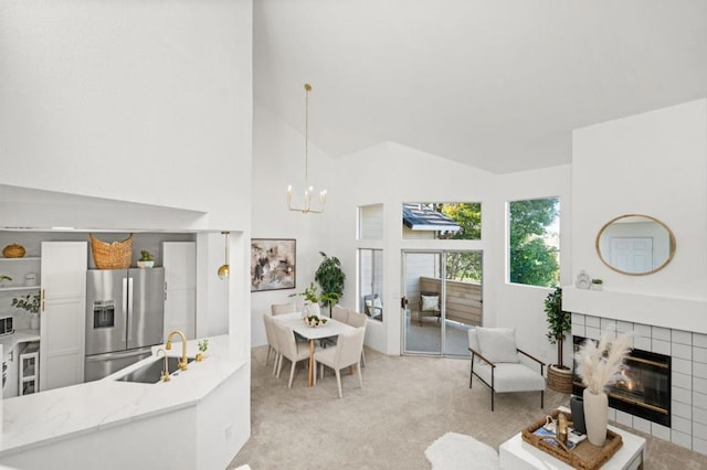 living room featuring light carpet, a fireplace, sink, a chandelier, and high vaulted ceiling