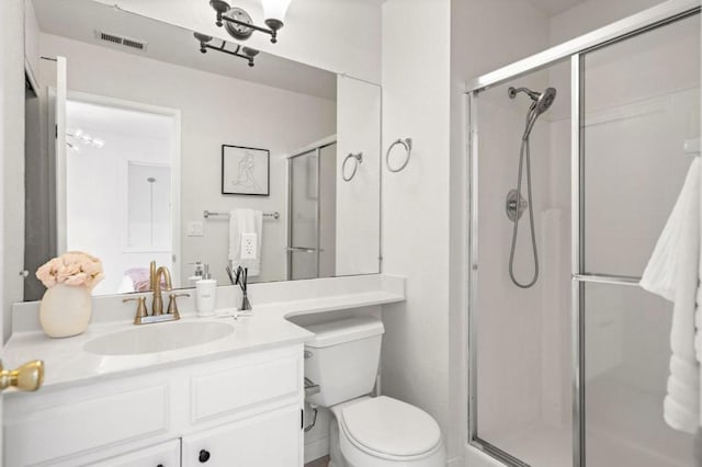 bathroom featuring a shower with door, toilet, and vanity