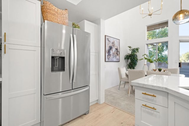 kitchen featuring white cabinets, decorative light fixtures, stainless steel fridge with ice dispenser, a notable chandelier, and light hardwood / wood-style flooring