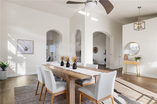 dining space featuring dark hardwood / wood-style floors, ceiling fan, and a high ceiling