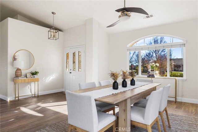 dining area featuring ceiling fan with notable chandelier, dark wood-type flooring, and lofted ceiling