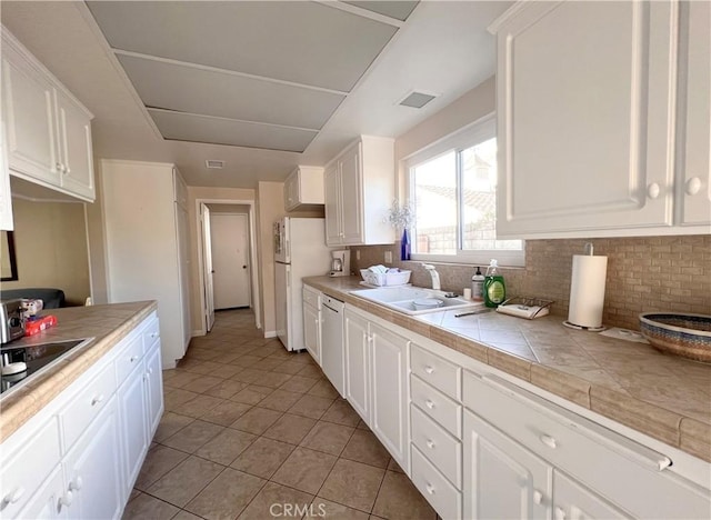 kitchen featuring light tile patterned floors, white cabinetry, decorative backsplash, and tile countertops