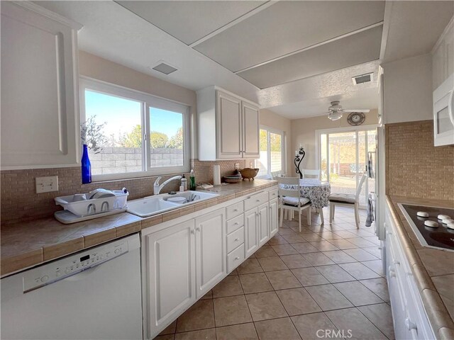 kitchen featuring white cabinetry, tile counters, dishwasher, stovetop, and sink