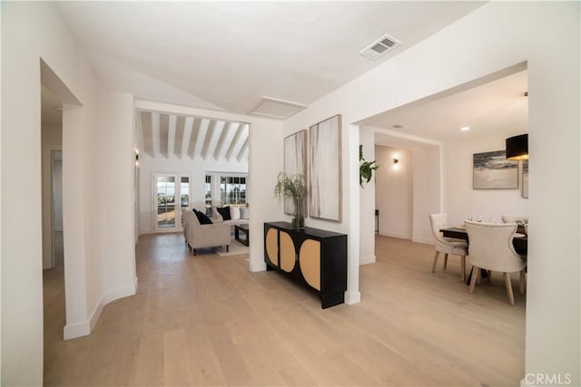 hallway with vaulted ceiling and light hardwood / wood-style flooring