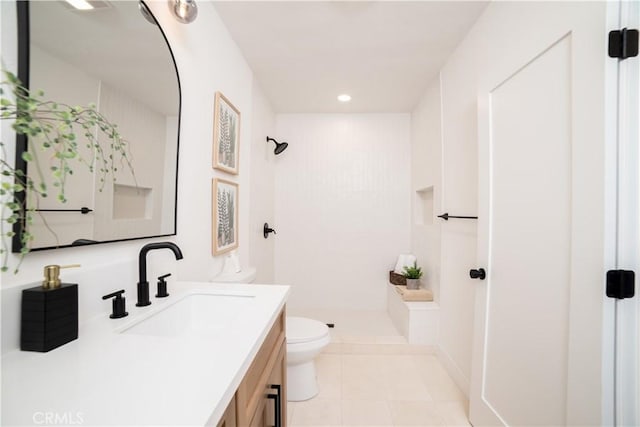 bathroom with toilet, vanity, tile patterned flooring, and a shower