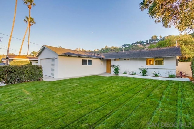 back of house with a garage and a lawn