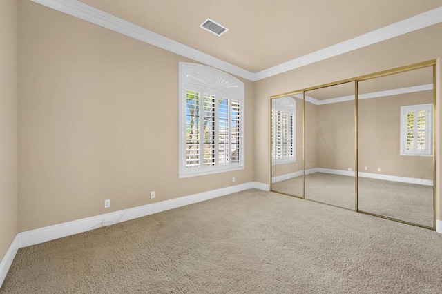 unfurnished bedroom with carpet floors, a closet, and crown molding