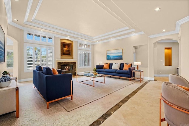 living room with a raised ceiling, a fireplace, and ornamental molding