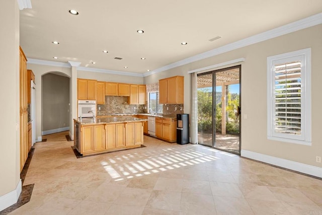 kitchen featuring decorative backsplash, white appliances, crown molding, and an island with sink