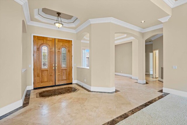 foyer featuring a wealth of natural light, crown molding, and a tray ceiling