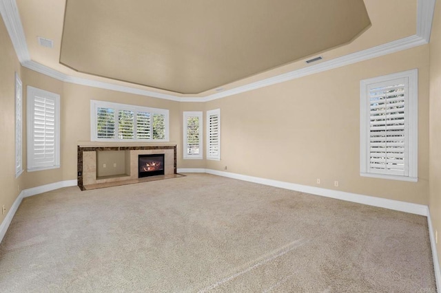 unfurnished living room with a high end fireplace, carpet, a raised ceiling, and ornamental molding