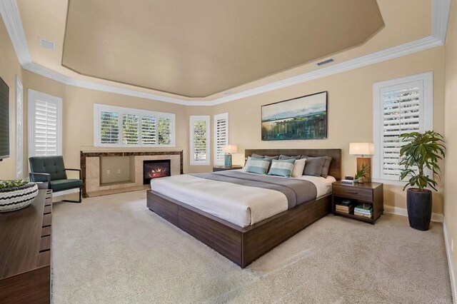 carpeted bedroom with a tray ceiling and ornamental molding