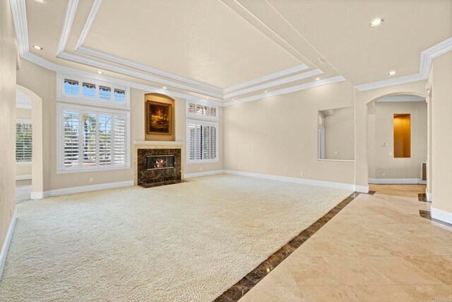 unfurnished living room featuring ornamental molding, a fireplace, and a tray ceiling