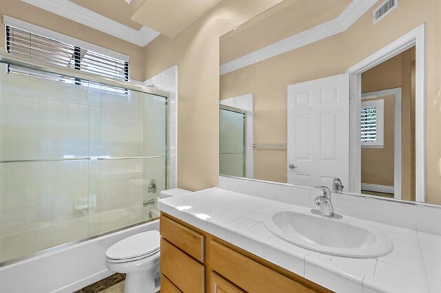 full bathroom featuring toilet, vanity, shower / bath combination with glass door, and ornamental molding