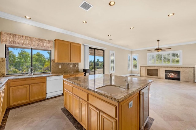 kitchen featuring ceiling fan, dishwasher, sink, a kitchen island with sink, and light stone counters