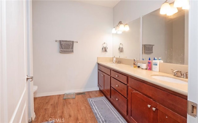 bathroom featuring toilet, vanity, and wood-type flooring