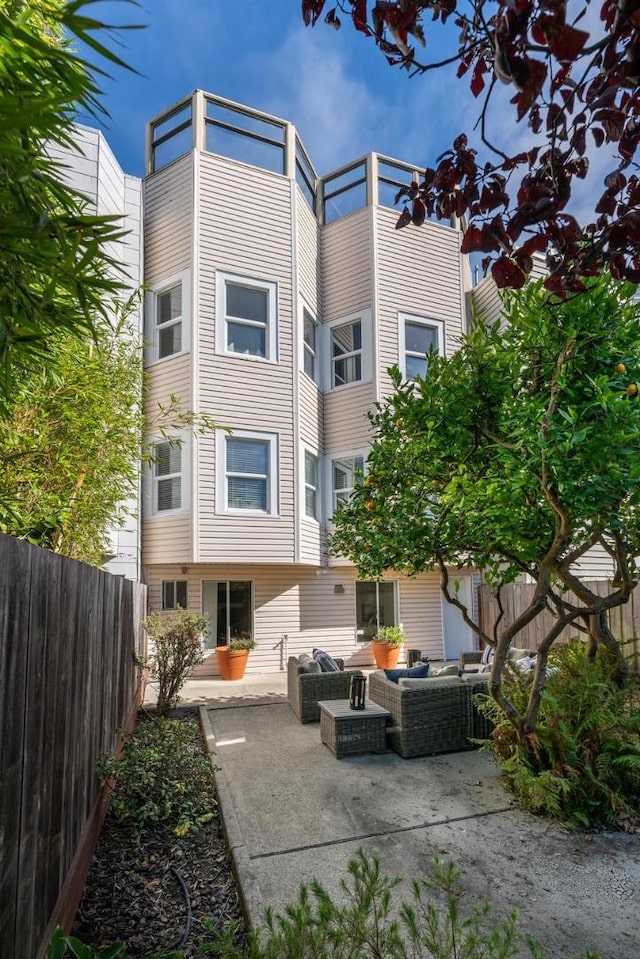 rear view of property featuring a patio and an outdoor living space with a fire pit